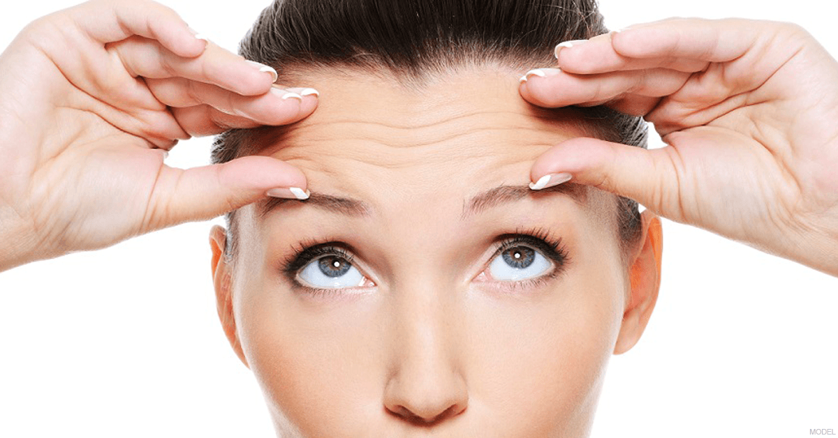 Woman examining her forehead lines
