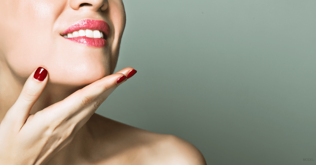 Close-up of a woman's hand touching her smooth neck following several nonsurgical skin and neck treatments.