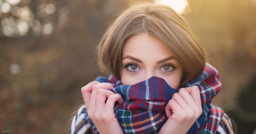 A woman wraps a scarf around her chin and cheeks to protect her skin after receiving several nonsurgical facial treatments.