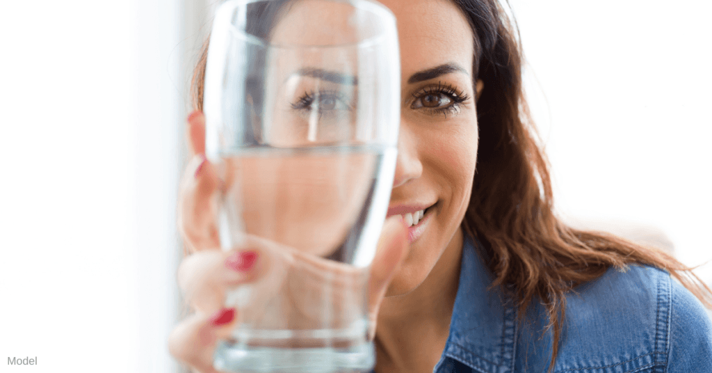 Woman holding glass of water in front of her face