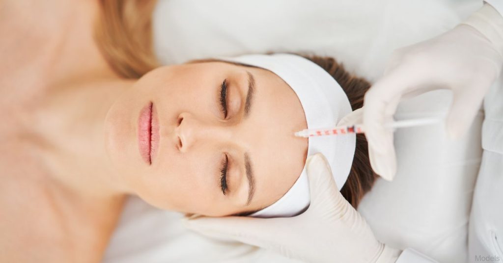 Woman receiving filler injections on her forehead by a physician (models)