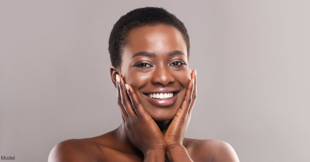 A woman holding her face in her hand (model)